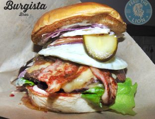 The Australian – Wagyu beef, fried egg, beetroot, turkey bacon, Applewood smoked cheese and onion marmalade, sauce, lettuce, tomato and gherkin in a brioche bun.